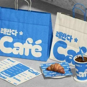 PSD Mockup Coffee Shop Branding, Blue and beige coffee shop paper bags with matching cups, menu, and croissant on branded…