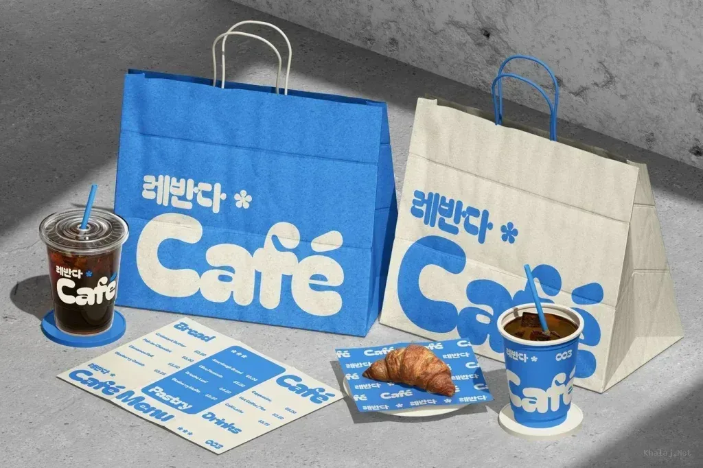 PSD Mockup Coffee Shop Branding, Blue and beige coffee shop branding with bags, cups, menu, and croissant on gray surface