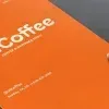 PSD Mockup Menu Presentation for Restaurant, Orange coffee menu mockup held by a hand on a gray surface